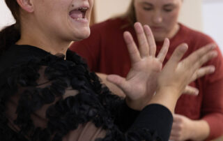 Jerneja uporablja znakovni jezik. V ozadju Daša gleda v vrečko.