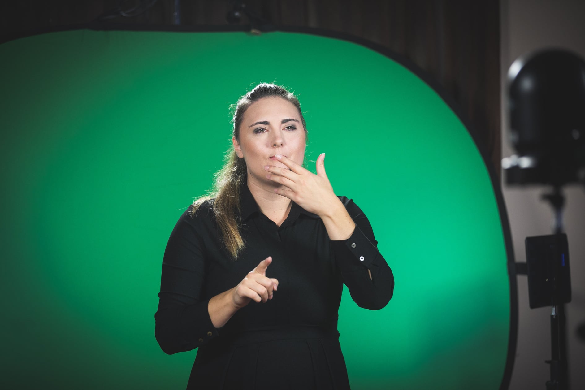 Daša Peperko tolmači v mednarodne kretnje, ozadje je zeleno.